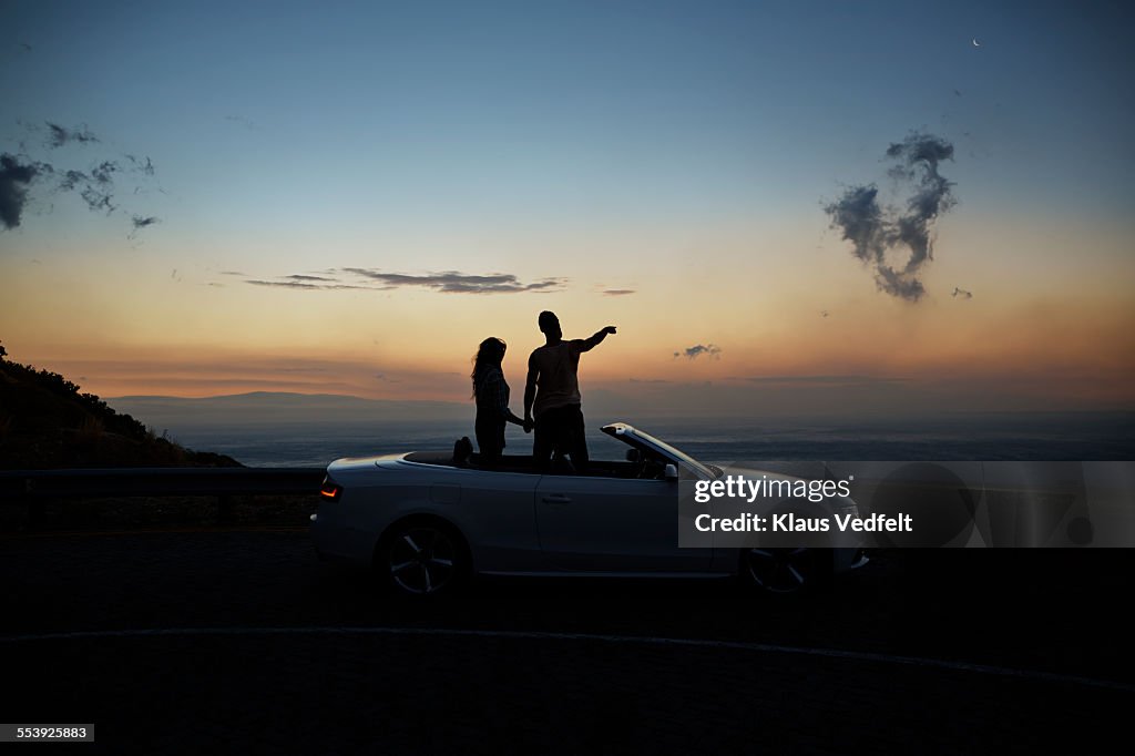 Couple holding hands and looking at sunset