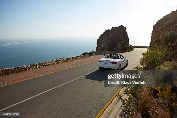 people with raised hands driving convertible car - highway blue sky car stock-fotos und bilder