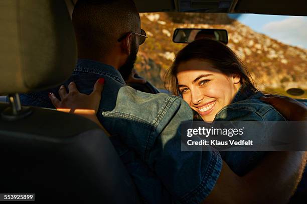 woman hugging boyfriend while driving car - driving romance stock-fotos und bilder