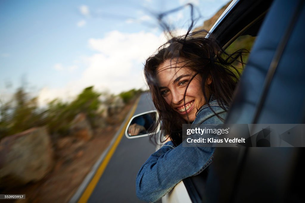 Woman sticking head out of car in motion