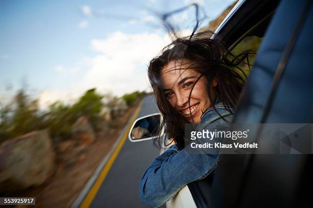woman sticking head out of car in motion - car window stockfoto's en -beelden