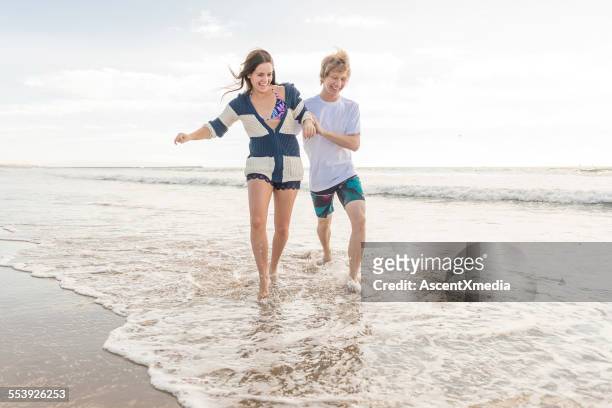 teen couple play in shallow surf, beach - ankle deep in water bildbanksfoton och bilder