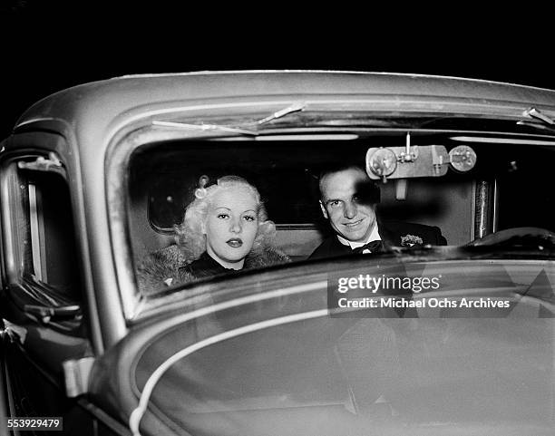 Actress Betty Grable and husband actor Jackie Coogan pose in their car in Los Angeles, California.