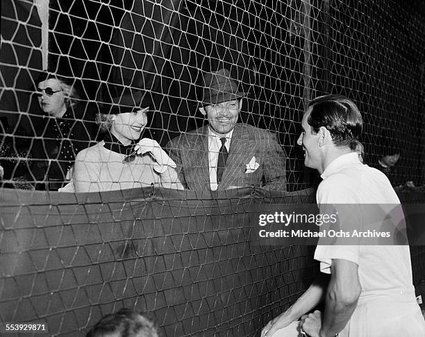 Actor Clark Gable and wife actress Carole Lombard talk with Bill Tildon during an event in Los Angeles, California.