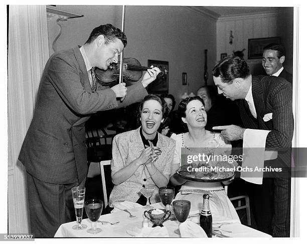 Actress Dorothy Lamour smiles as her husband Herbie Kaye serenades her and actress Gail Patrick during a party in Los Angeles, California.