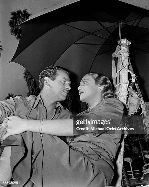 Actor Douglas Fairbanks Jr poses with Mary Lee Eppling under an umbrella in Los Angeles, California.