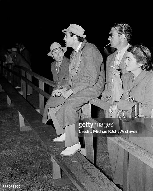 Actor Henry Fonda sits on a railing next to actor Gary Cooper and his wife actress Veronica Balfe during an event in Los Angeles, California.