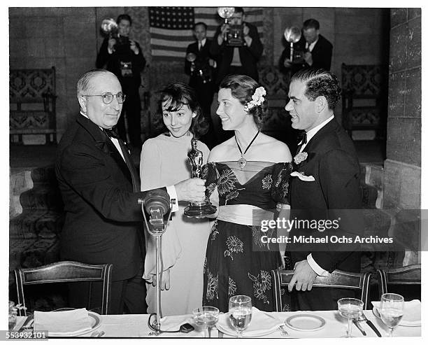 Producer Louis B. Mayer poses as he presents the Oscar to actress Luise Rainer for the Academy Award for Best Actress and Mrs Louise Tracy accepting...