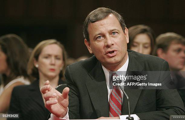 Washington, UNITED STATES: Judge John Roberts answers a question 13 September 2005 as his wife Jane listens during the second day of his confirmation...