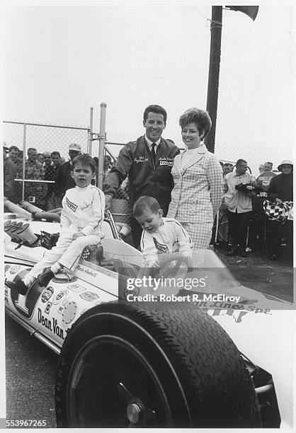 Italian-born American race car driver Mario Andretti and his wife Dee Ann stand with his sons, Mike and Jeff, perched on his car, May 1967.