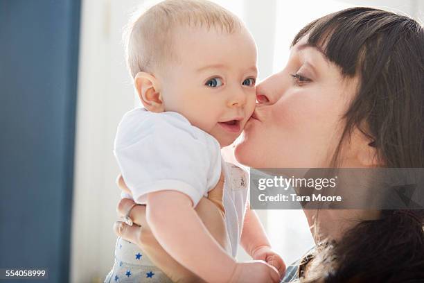 mother kissing smiling baby - babyhood bildbanksfoton och bilder