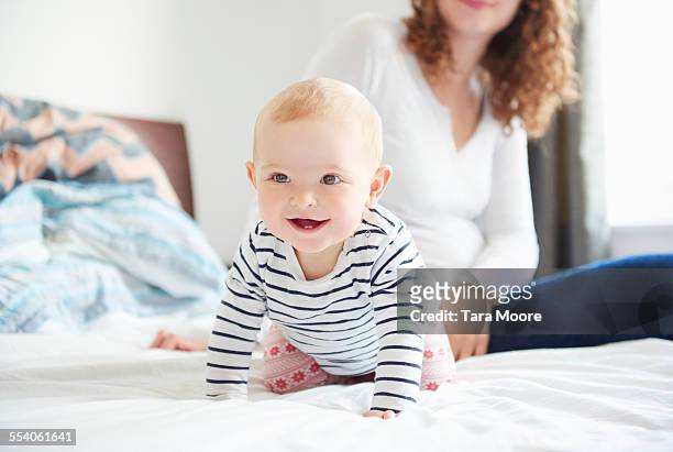 happy baby and mother on bed - crawling stock-fotos und bilder