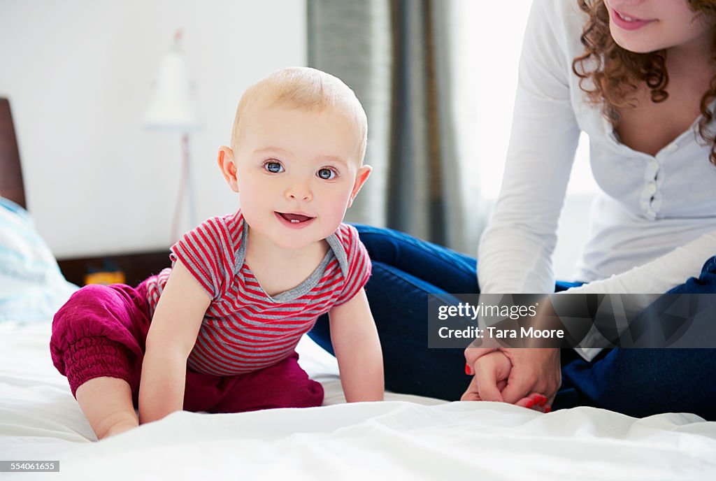 Mother and baby on bed playing