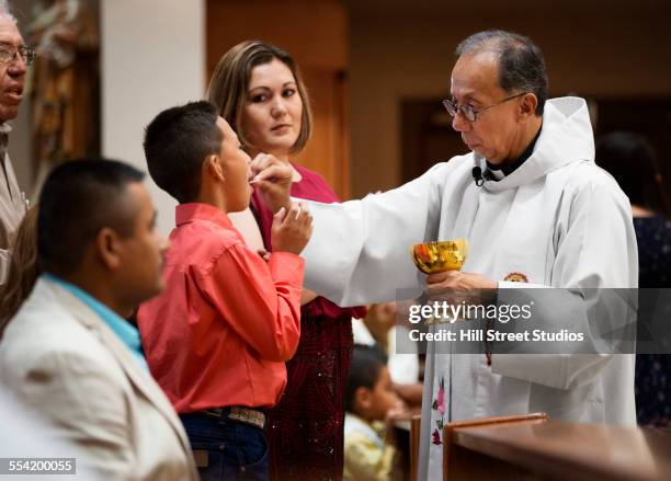 priest giving communion during mass in catholic church - mis stockfoto's en -beelden