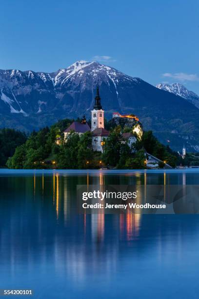 church tower and mountains reflecting in still lake - julianische alpen stock-fotos und bilder