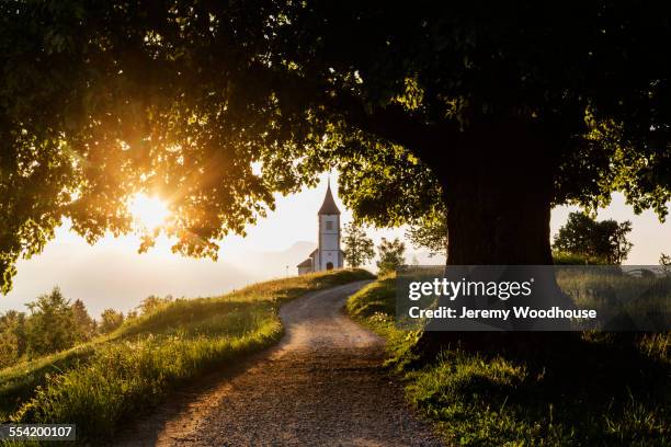 dirt road leading to remote hilltop church - church sunset rural scene stock pictures, royalty-free photos & images