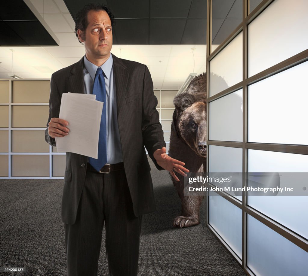 Bear stalking nervous businessman in office