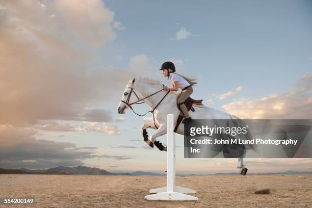 caucasian girl riding horse over gable in race - evento ecuestre fotografías e imágenes de stock