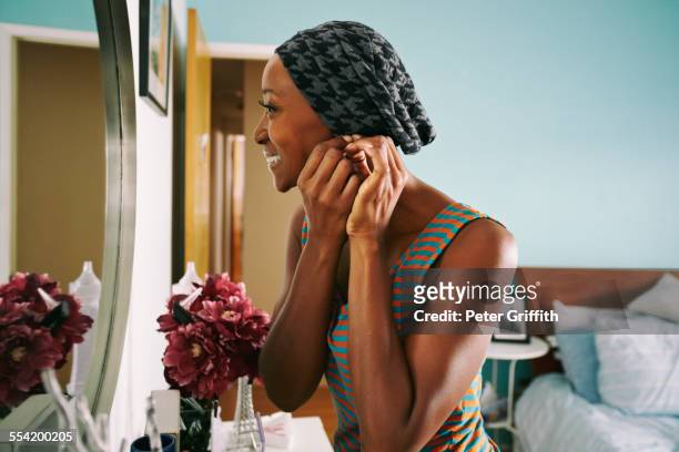 smiling african american woman attaching earring - changing your life stockfoto's en -beelden