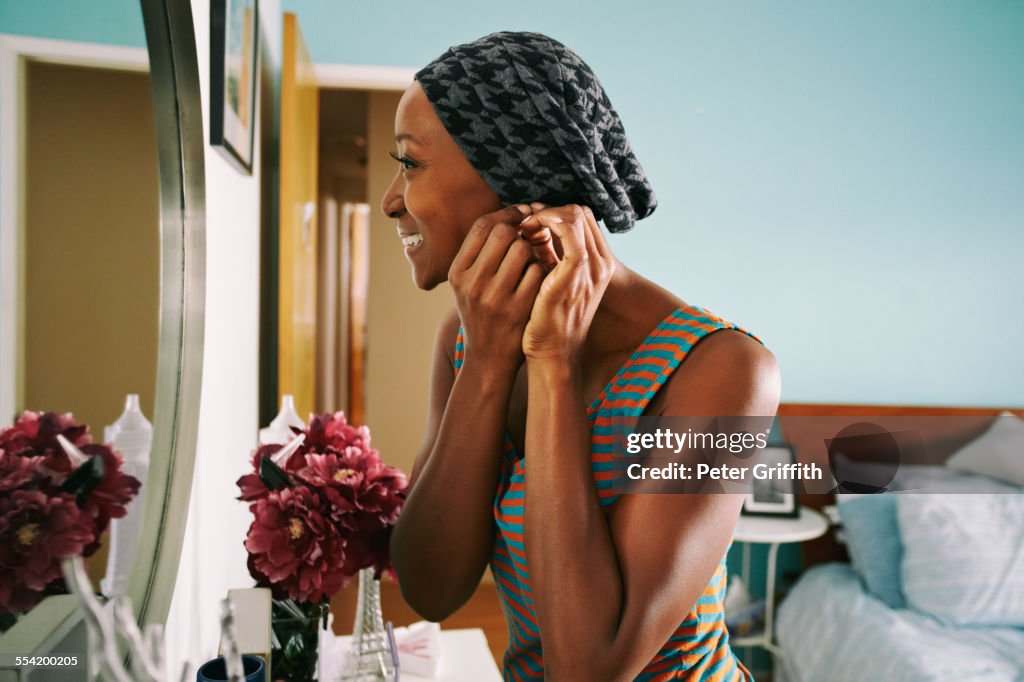 Smiling African American woman attaching earring