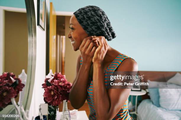 smiling african american woman attaching earring - black mirror imagens e fotografias de stock