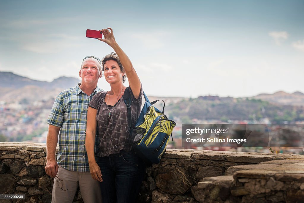 Caucasian couple taking cell phone photograph together on rooftop