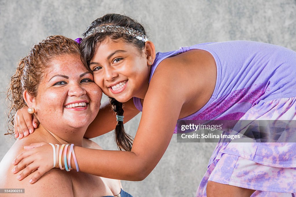 Smiling Hispanic mother and daughter hugging