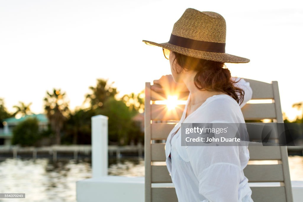 Caucasian woman admiring sunset from deck chair