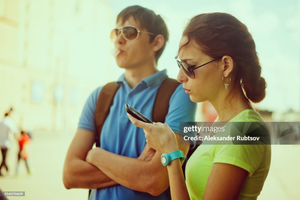Caucasian woman using cell phone with boyfriend outdoors