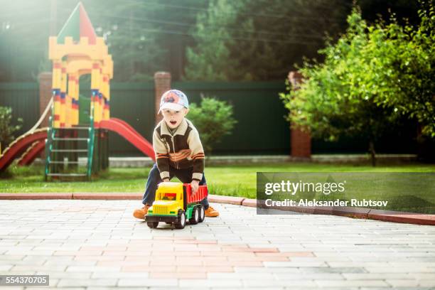 caucasian boy playing with toy truck in playground - toy truck stock pictures, royalty-free photos & images