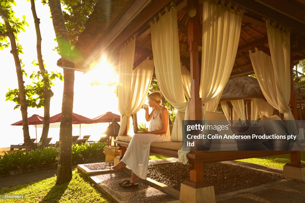 Caucasian woman relaxing in cabana on tropical beach