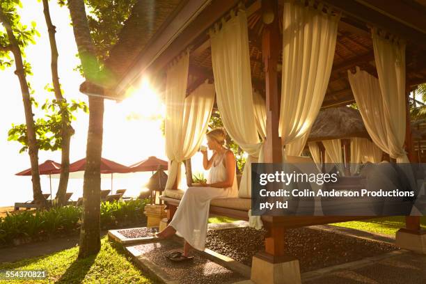 caucasian woman relaxing in cabana on tropical beach - bali luxury stock pictures, royalty-free photos & images