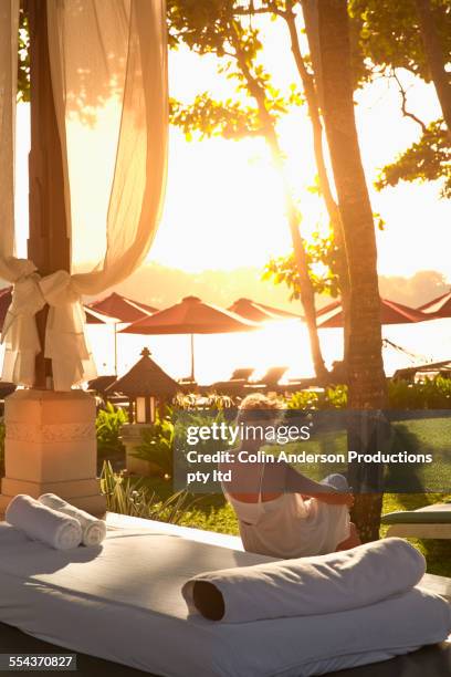 caucasian woman relaxing on daybed at beach - bali spa stock pictures, royalty-free photos & images