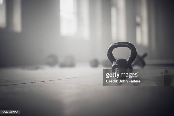 close up of kettlebell weights on floor of dark gym - kettle bells stockfoto's en -beelden