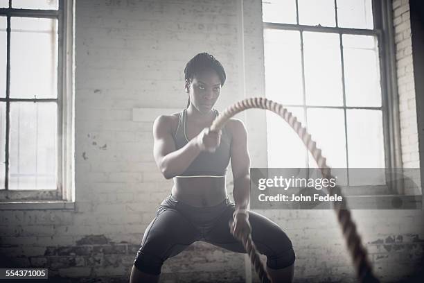 black woman tossing ropes in dark gym - john hale stock pictures, royalty-free photos & images