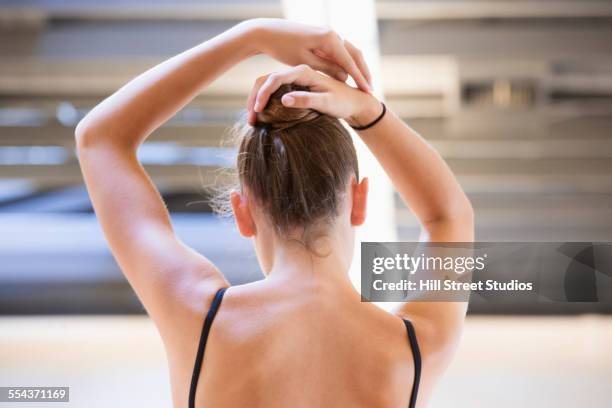 ballet dancer tying hair in bun in studio - hair bun stockfoto's en -beelden