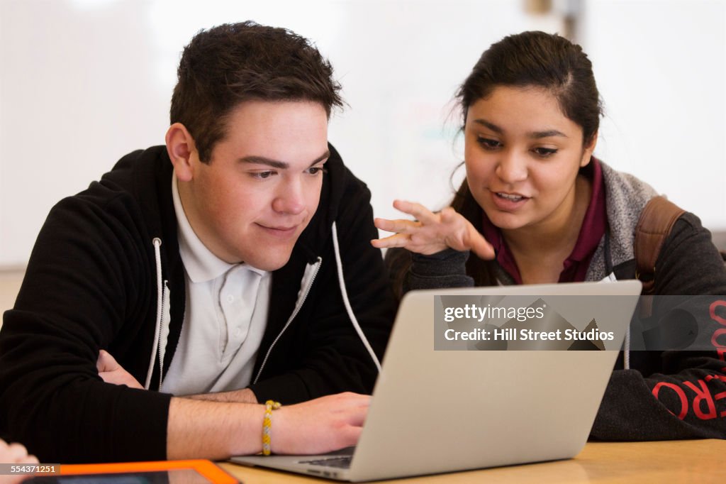 Students using laptop at desk in class