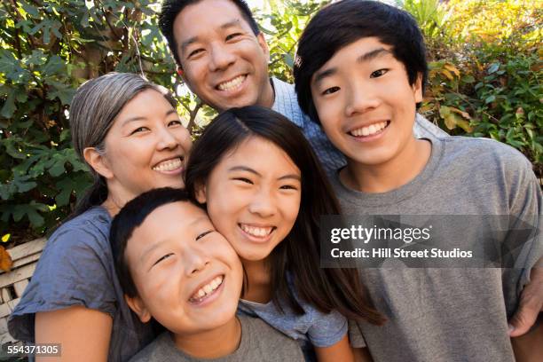 asian family smiling in garden - wange an wange stock-fotos und bilder