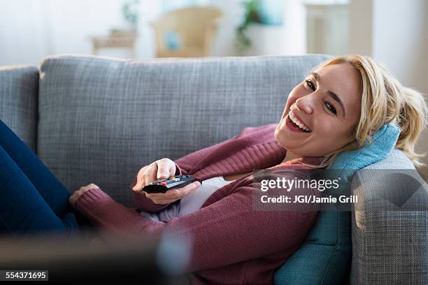 caucasian woman watching television on sofa - zusehen stock-fotos und bilder