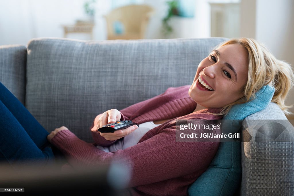 Caucasian woman watching television on sofa