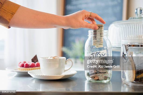 caucasian woman putting money in tip jar - tip jar fotografías e imágenes de stock