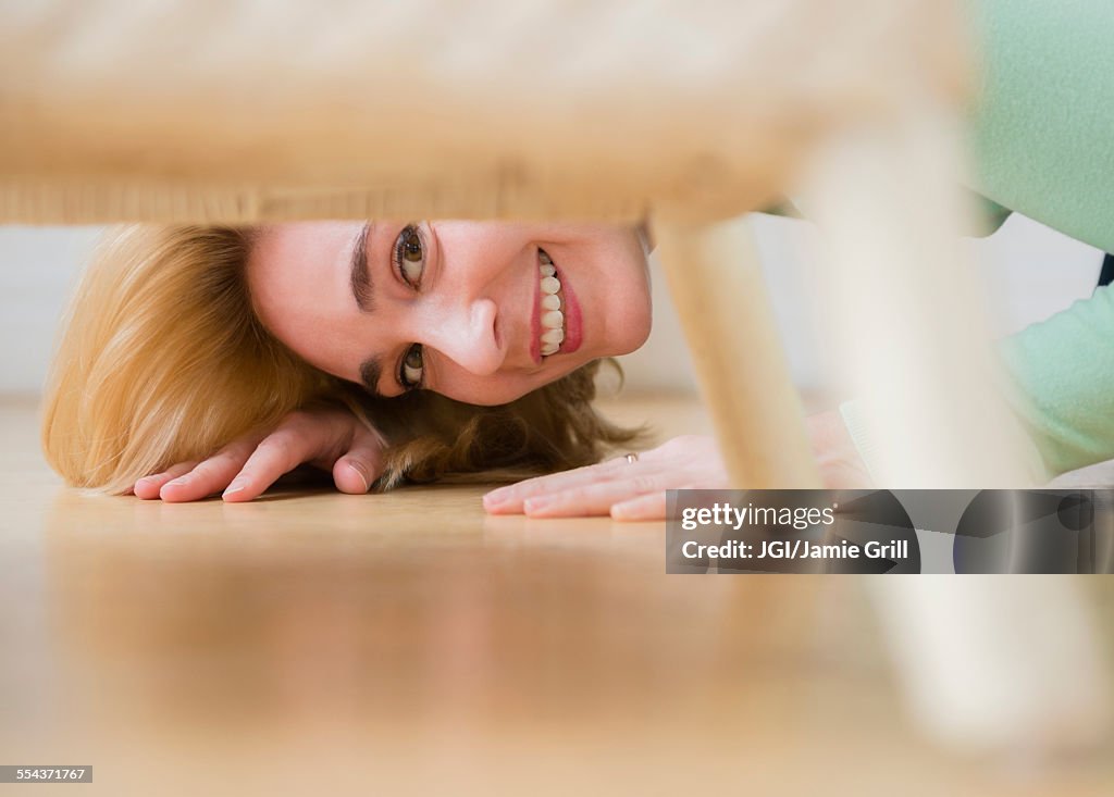 Caucasian woman peeking under chair