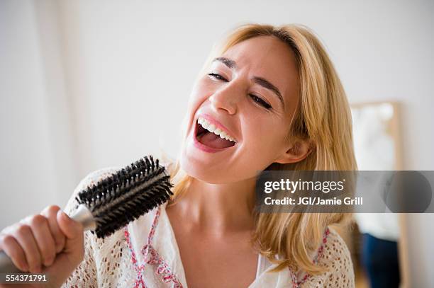 caucasian woman singing into hairbrush - microphone mouth stock-fotos und bilder