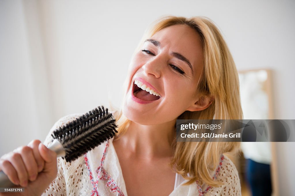 Caucasian woman singing into hairbrush