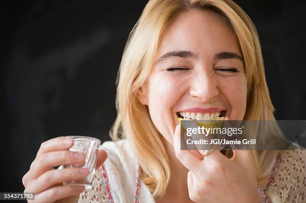 caucasian woman eating lemon slice with liquor shot - tequila tasting stock pictures, royalty-free photos & images