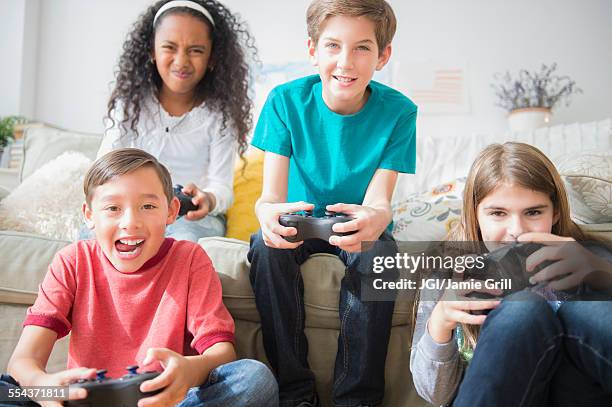 children playing video games on sofa - game four stockfoto's en -beelden