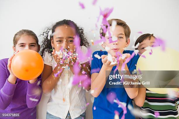 children blowing party confetti and balloons - child balloon studio photos et images de collection