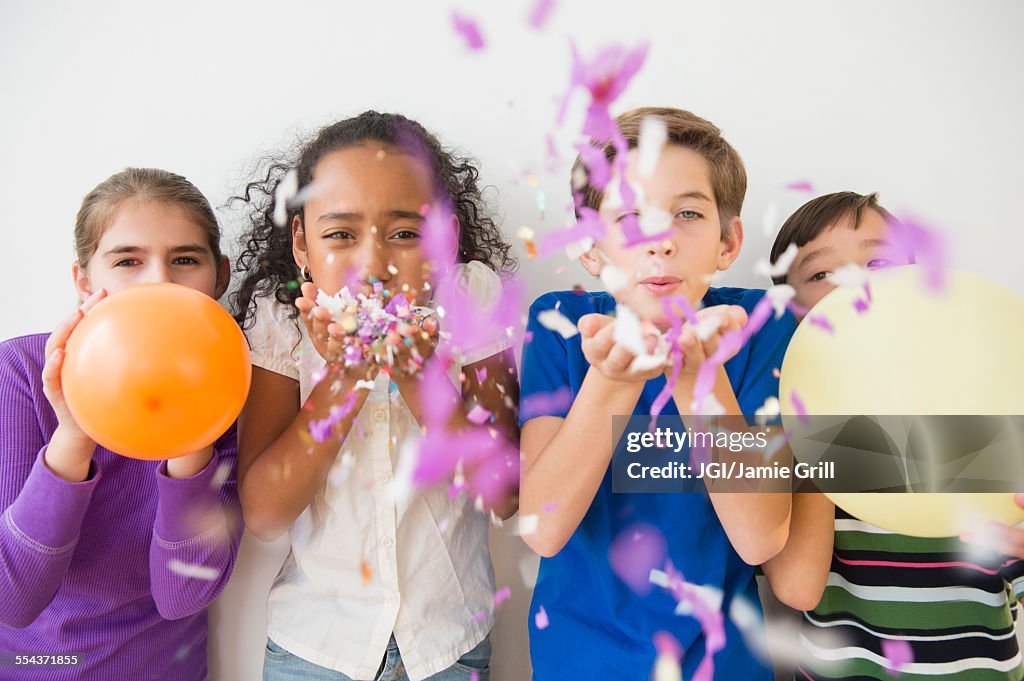 Children blowing party confetti and balloons