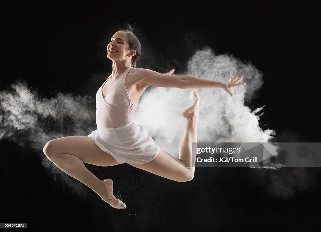 Hispanic dancer leaping in cloud