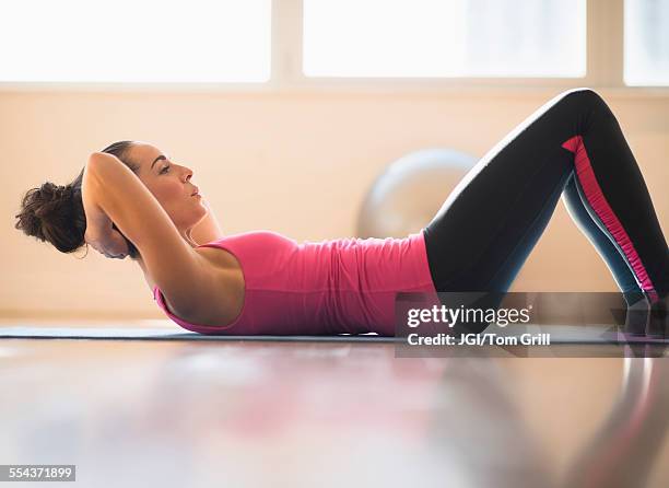 close up of hispanic woman doing sit-ups in gym - sit ups stockfoto's en -beelden